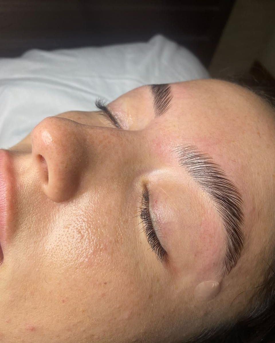 Client lying back with freshly laminated, brushed-up brows at Aurora