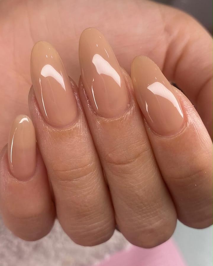 Glossy soft nude manicure on long almond-shaped nails